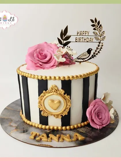 A chic and stylish birthday cake for Tanna, featuring black and white stripes, gold accents, and beautiful pink roses.