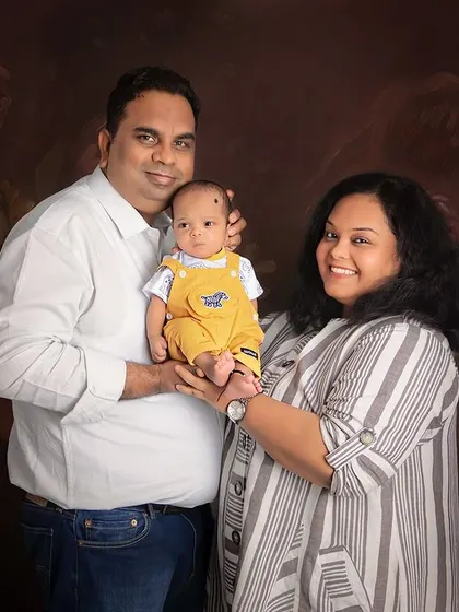 A beautiful family of three. This portrait showcases the joy and pride of new parents as they hold their little one, creating a memory to last a lifetime.