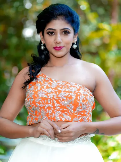 A modern traditional look for a photoshoot. The makeup features a bold fuchsia lip and defined eyes, which pop against the embroidered orange and white outfit.