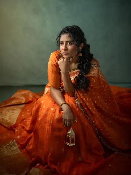 Holding a small, vintage lantern, Vennela's portrait takes on a storytelling quality. The prop adds a touch of nostalgia and symbolism, while the painterly light and deep colors create a moody and atmospheric scene.