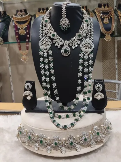 For brides who love a modern yet regal look, this is a stunning Victorian-inspired diamond and emerald look-alike set. It includes a choker, a layered long necklace, matching earrings, maang tikka, and a delicate waist belt.