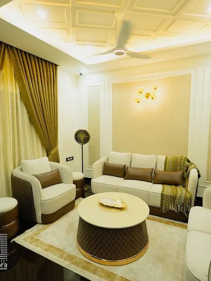 A truly royal living room setting I created for a client. The quilted cream and brown sofa set, complete with matching ottomans and a circular coffee table, exudes opulence, enhanced by the coffered ceiling and elegant wall paneling.