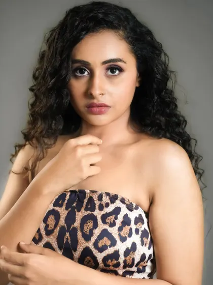 A strong and direct headshot. The animal print top and curly hair give this portrait a bold and confident character, great for an actor's range.
