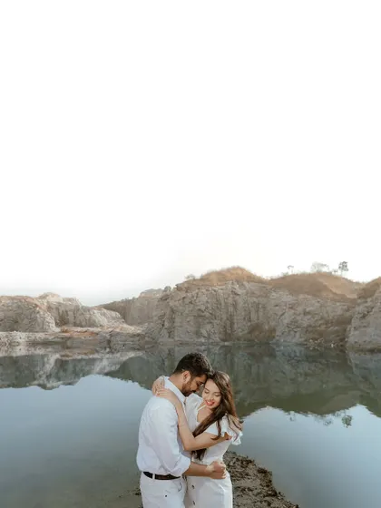 An intimate embrace by a serene quarry lake. The rugged rocks and calm water provide a beautiful contrast, making for a dramatic and romantic pre-wedding portrait.
