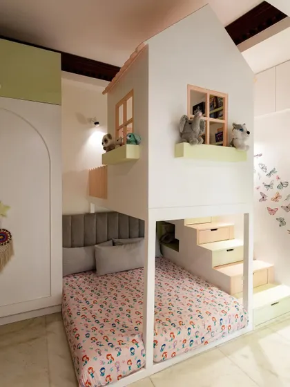 I love finding clever ways to use space. For this room, I designed a custom house-shaped bunk bed with built-in stairs that double as storage drawers. The soft pastel colors and cozy lower bunk create a perfect little haven for sleep and play.