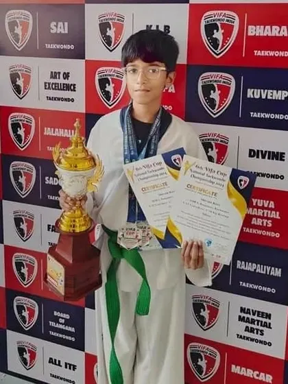This student proudly displays his trophy and certificates after a successful national Taekwondo competition.