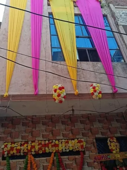 The upper portion of a house decorated with pink and yellow drapes and small floral arrangements.