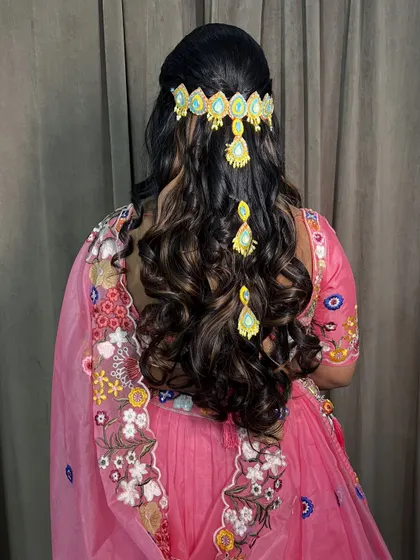 A modern Haldi hairstyle with open curls and a statement hair accessory, perfect for a lehenga.