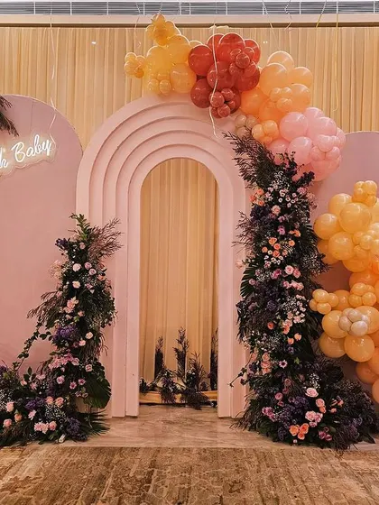 A closer look at the stunning "Oh Baby" backdrop. The combination of the arched panels, a delicate neon sign, and a mix of balloons and fresh flowers creates a sophisticated and modern focal point for any baby shower.