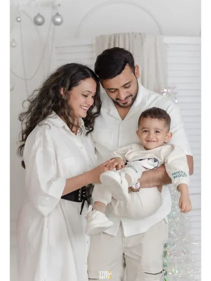 A happy family of three, their smiles as bright as the Christmas decorations.