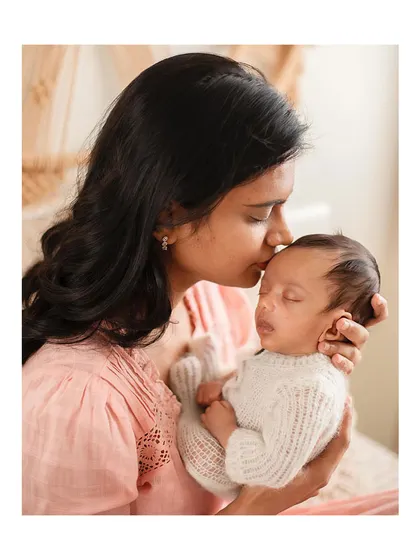 A mother's tender kiss for her newborn baby.