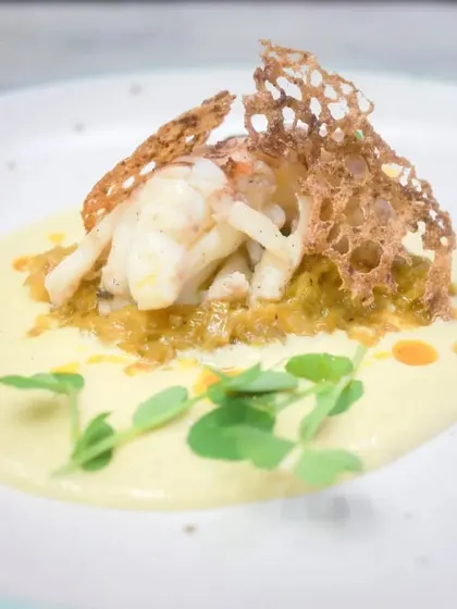 For a taste of luxury, I present my confit lobster tail. It's served on a bed of saffron leeks fondue with a corn and lemongrass velouté, finished with a touch of chili oil.
