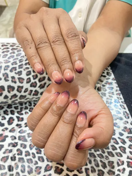 A darker, more dramatic take on the ombre trend. This design uses a deep burgundy color that fades from the tips into a natural nude base on rounded nails, creating a chic and moody effect.