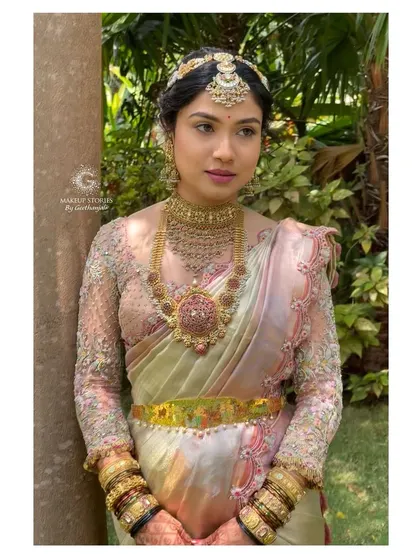 A beautiful outdoor portrait of Drutha. The natural light highlights the soft texture of her makeup and the intricate details of her bridal blouse.