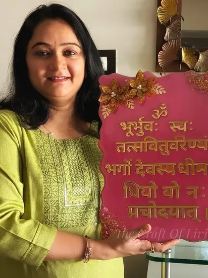 Here I am, holding a custom-made Gayatri Mantra plaque. It was a joy to create this piece, which blends sacred verses with floral artistry, for a client's home.