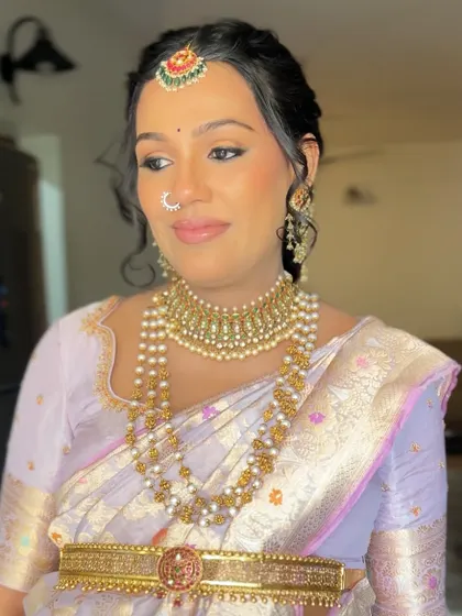 A lovely client ready for a family function. This light purple silk saree is draped neatly with a gold belt, and her hair is styled in a soft updo.