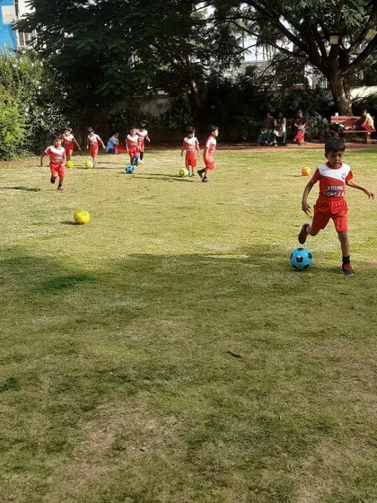A young boy kicks the ball during a drill, practicing his technique in a supportive environment.