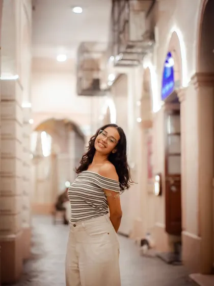 A beautiful portrait taken in a warmly lit alleyway. The leading lines of the corridor draw the eye directly to the subject.
