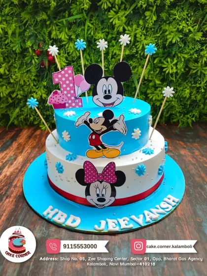 A classic two-tier Mickey and Minnie Mouse cake for a first birthday. The bright blue and white design with character toppers is a timeless choice for a little one's celebration.