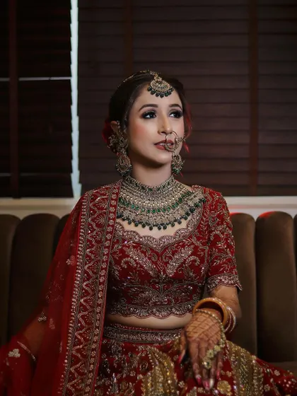 A classic bridal pose, showing off the intricate details of her makeup, jewelry, and lehenga.