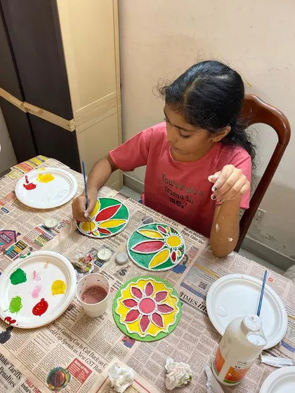 A young artist completely focused on her creation during our Diwali Lippan Art workshop. She is carefully painting a traditional design on a tea light holder, learning about patterns and colors while making a beautiful craft for the festival of lights.