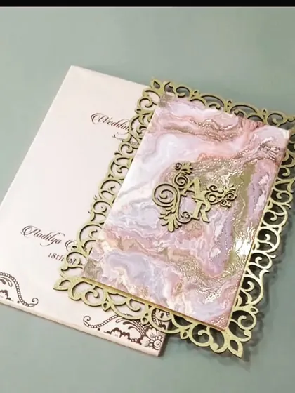 A modern invitation featuring a laser-cut acrylic overlay with a marble effect and a wooden monogram. The design is edgy and sophisticated.