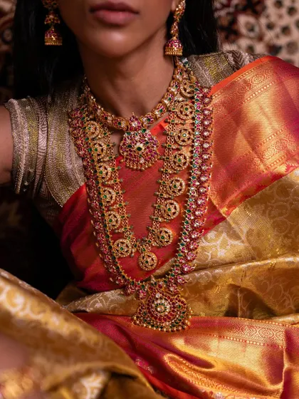 A close-up on the magnificent bridal jewelry, which perfectly complements the golden sheen of the Kanchipuram tissue silk saree.