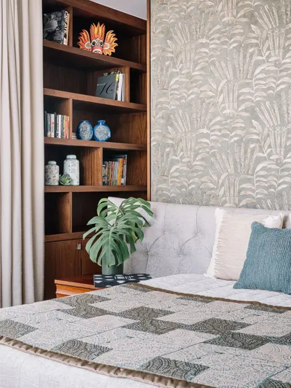 A close-up view of the custom-designed headboard partition. The built-in bookshelf is not only a practical storage solution but also a place to display personal items and art, making the bedroom feel truly unique to its owner.