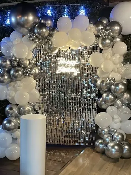 Another angle of the stunning silver and white balloon arch. The addition of fairy lights behind the backdrop adds an extra layer of sparkle to the celebration.