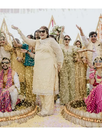 A vibrant group photo from the Haldi, with the couple and their guests all smiles, showered in flower petals.