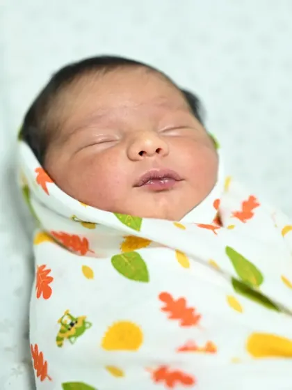 A serene close-up of a sleeping newborn, peacefully swaddled. Capturing these quiet, beautiful details is just as important as capturing the big celebration moments.