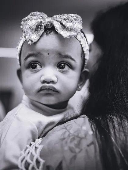 A striking black and white portrait of a baby girl looking on with wide, curious eyes. This style creates timeless and emotive images.