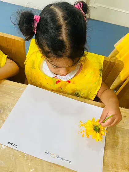 Dressed in yellow for our color-themed day, this child discovers how to make prints with a flower. This activity connects art with the natural world.