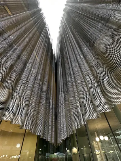 Looking up at the draped metal mesh ceiling, an innovative use of industrial material to create an ethereal effect.