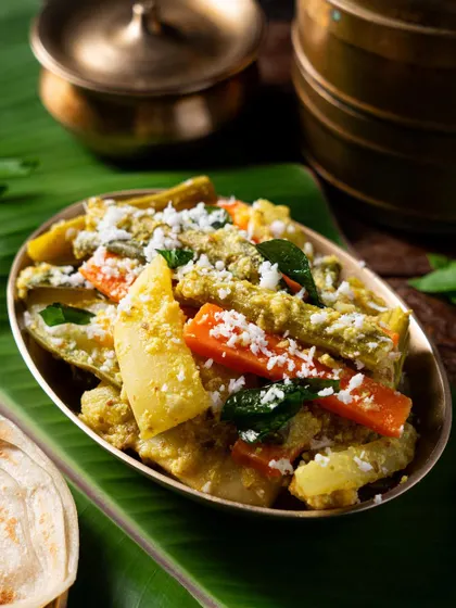 A close-up of Avial, a mixed vegetable stew from Kerala. The shot highlights the variety of vegetables and the creamy coconut-based sauce.