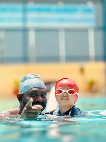 A coach points forward, encouraging a young swimmer to look ahead. This simple gesture is part of how we teach body alignment and focus, even at a very early age.