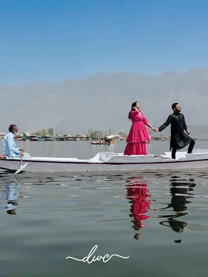 A breathtaking pre-wedding shot of a couple on a shikara in Kashmir's Dal Lake, with the vast mountains creating a majestic backdrop.