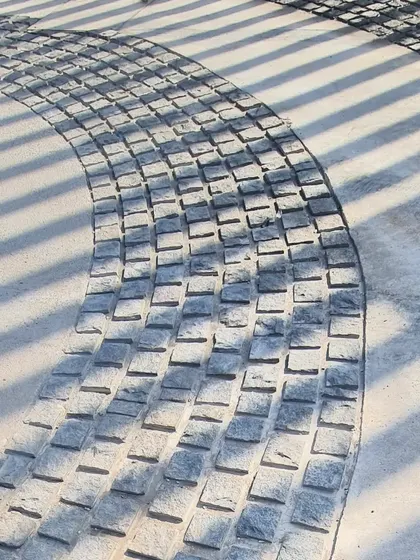 The texture of the hand-laid cobblestones contrasts with the smooth concrete, adding a tactile richness to the ground plane.