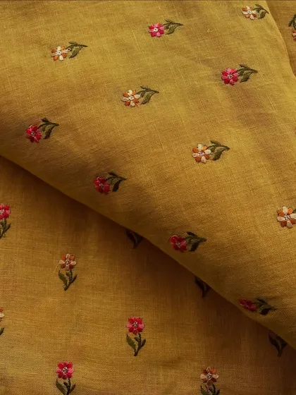 This embroidered linen in a mustard yellow hue with small floral butis is a charming choice for a bright and cheerful outfit.