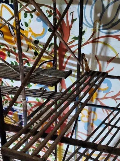 A detail shot through the scaffolding, capturing the texture and color of the emerging Kalamkari artwork.