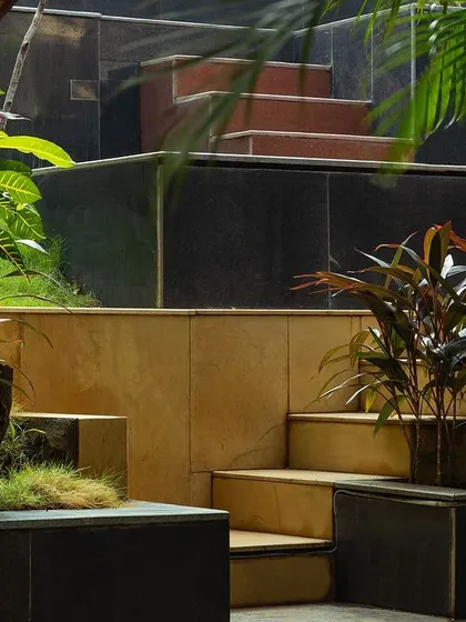 **Nepean Greens, Mumbai:** The interplay of materials and levels is highlighted in this detail shot. The design creates a rich tactile and visual experience, with planters bringing greenery right up to the seating areas.
