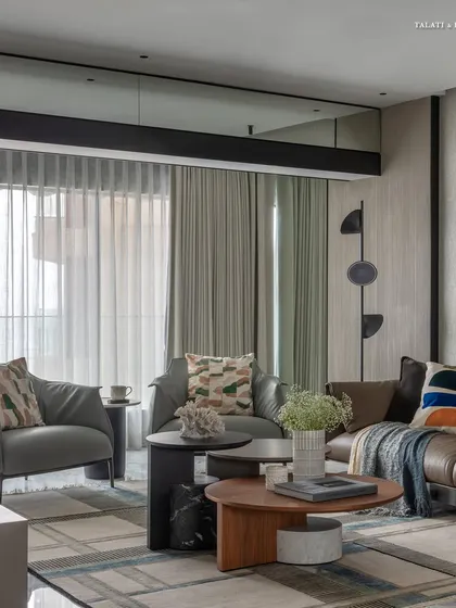 This living room for an art collector blends playful designs with a contemporary minimalist vibe. Custom statement pieces, like the abstract floor lamp and colorful artwork, bring the space to life against the stunning backdrop of Mumbai's sea-facing skyline.
