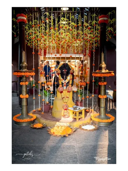 A sacred space set up for a naming ceremony ritual. The area is defined by a canopy of flowers and traditional brass lamps, creating a divine atmosphere.