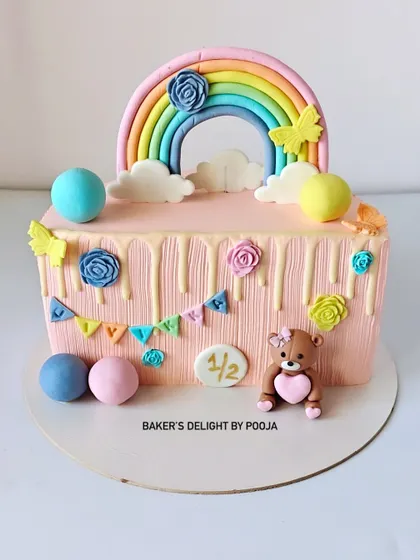Half the age, double the cuteness! This half-birthday cake is a rectangular design with a pastel rainbow, a sweet fondant teddy bear, and colorful bunting to celebrate the six-month milestone.