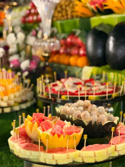 A feast for the eyes and a treat for the taste buds! This display features carved fruit bowls filled with watermelon and lychee, surrounded by other artfully arranged fruits.