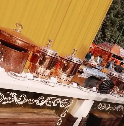 Another angle of our outdoor buffet setup, showcasing the line of copper serving pots and the festive atmosphere created by the colorful umbrellas and decor in the background.
