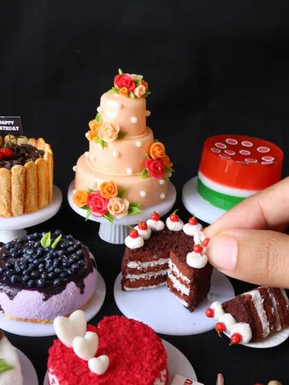 A hand holding a slice of the layered red velvet cake, showing the detail and realism of the creation.