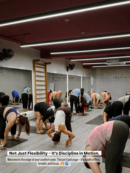 The class in a deep forward bend, showcasing discipline in motion. This moment captures the edge of the comfort zone, where the real work of yoga begins.