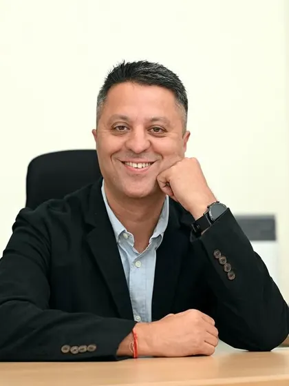 A friendly and engaging headshot. The slight lean-in and smile create a connection with the viewer, making this an excellent choice for a profile picture.