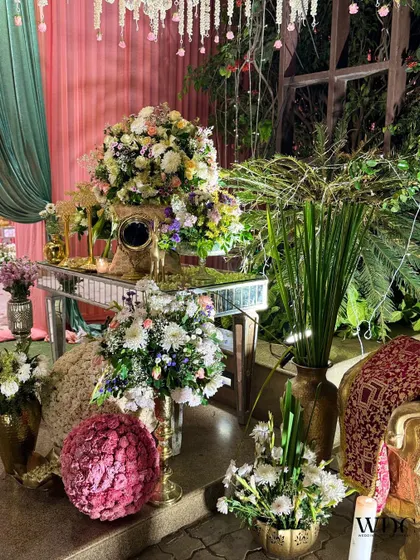 A lush and overflowing floral display on a mirrored table, combining various flowers and greens to create a sense of natural abundance and luxury.